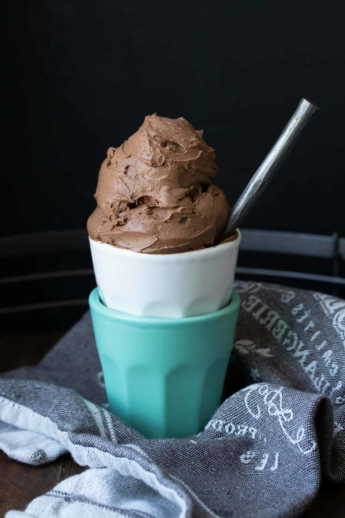 Scoops of chocolate ice cream in teal and white bowls. 