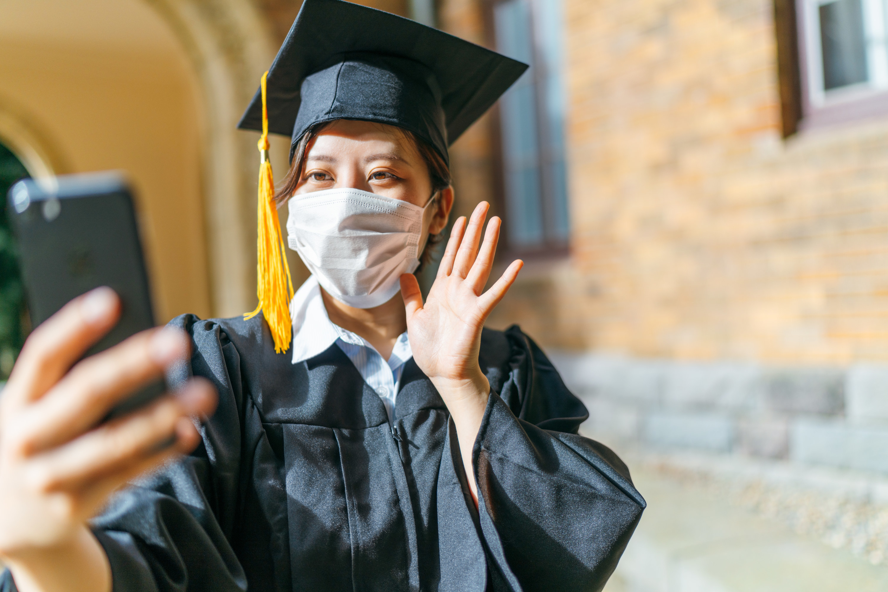 Student taking a selfie in their graduation cap and gown