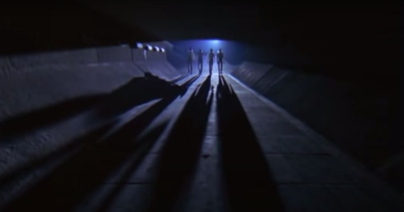 Four people walking in a tunnel