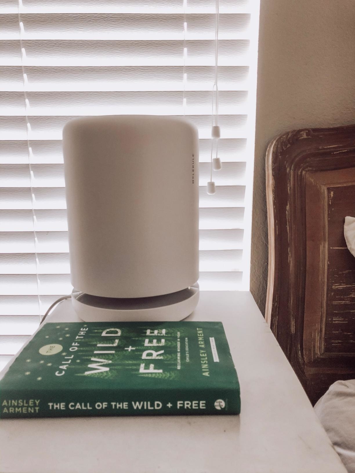 the air purifier sitting on a night stand next to a bed