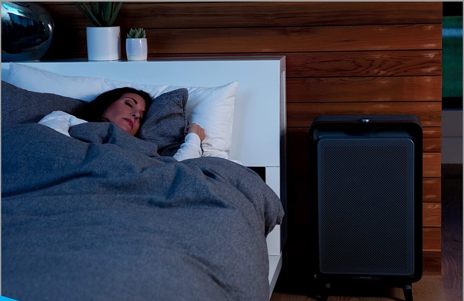 A black rectangular air filter next to a model's bed
