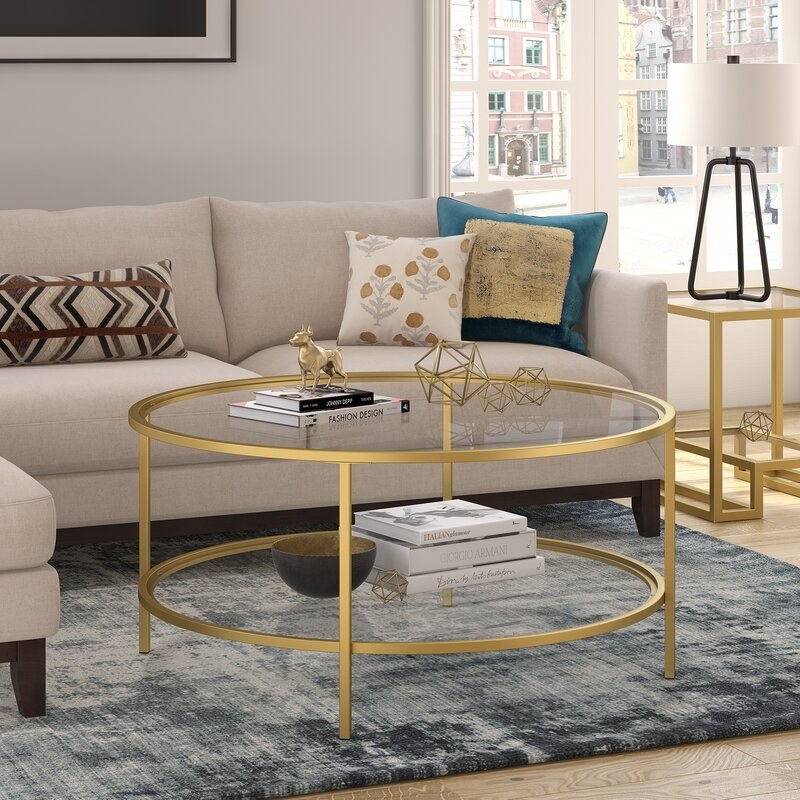 glass and satin gold finish coffee table with books and home decor items