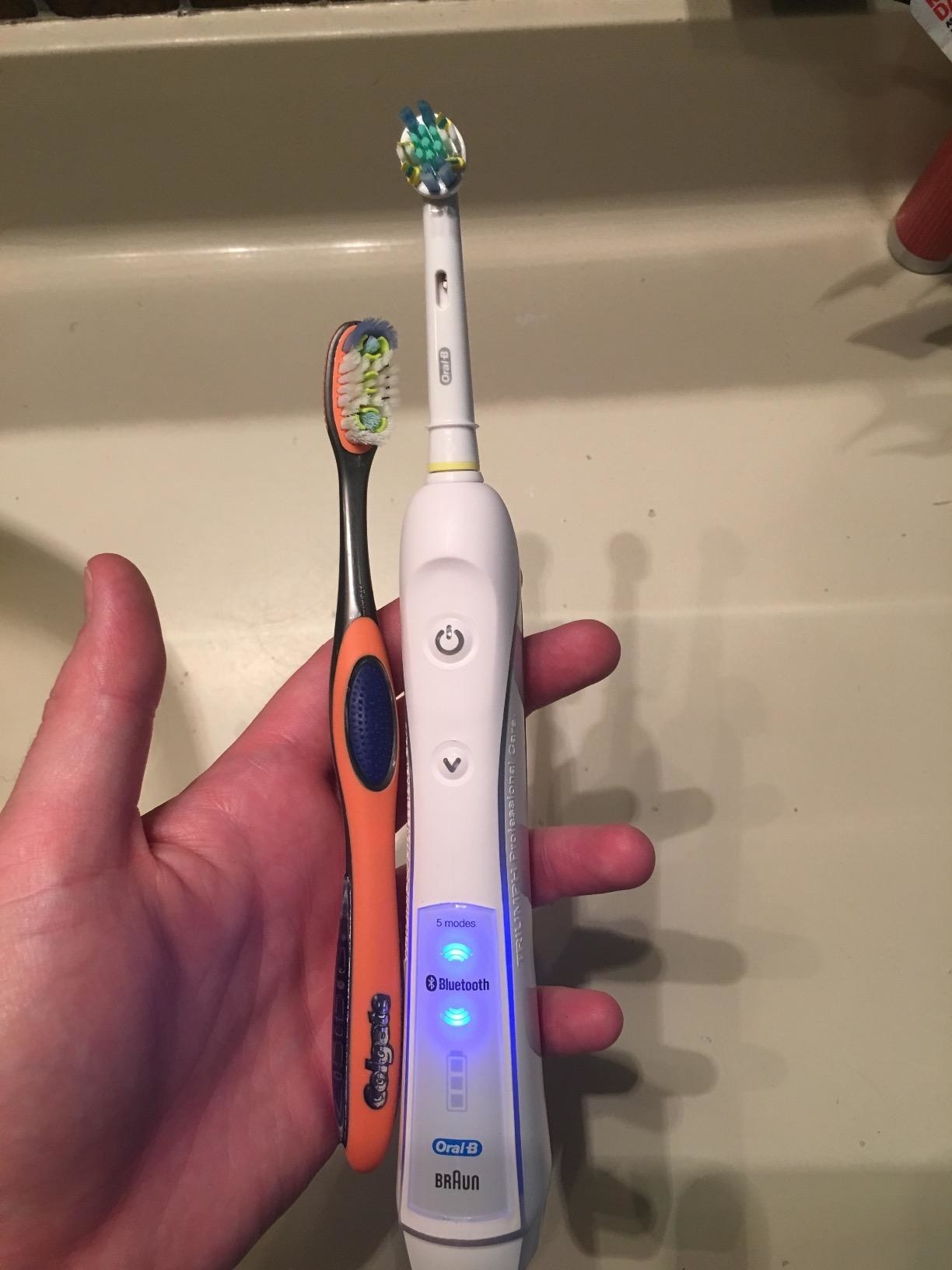reviewer holding the electric toothbrush and a manual toothbrush, and the electric toothbrush is clearly bigger and sleeker