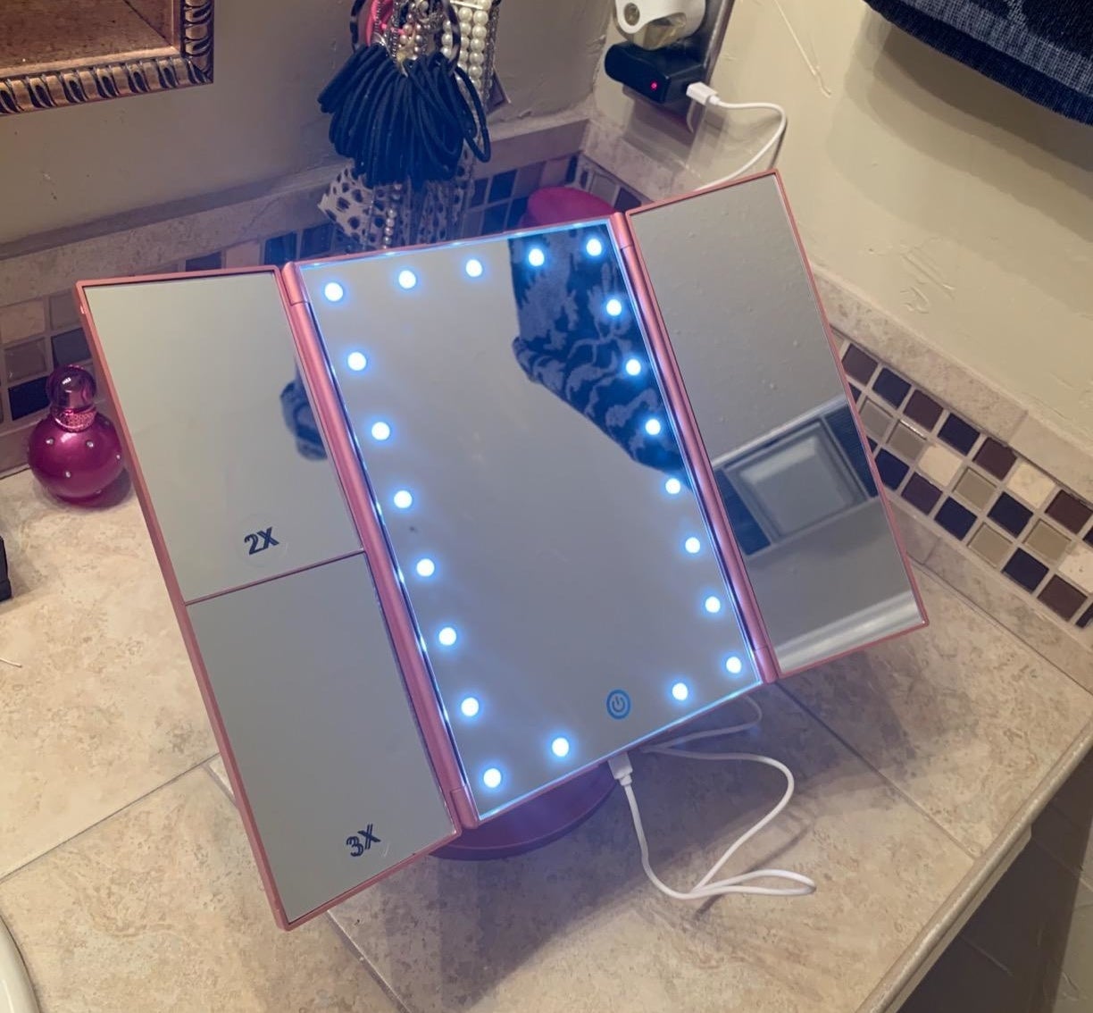 reviewer&#x27;s lighted makeup mirror in pink on a bathroom counter