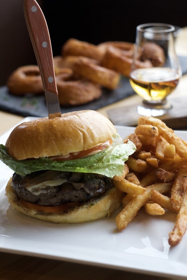 Close-up of cheeseburger with crispy french fries on a white plate