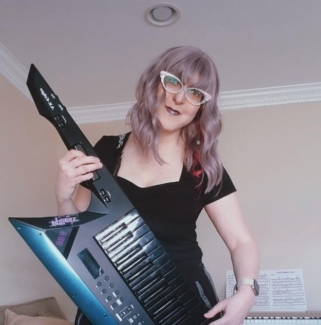 Woman plays keytar keyboard slung over her right shoulder