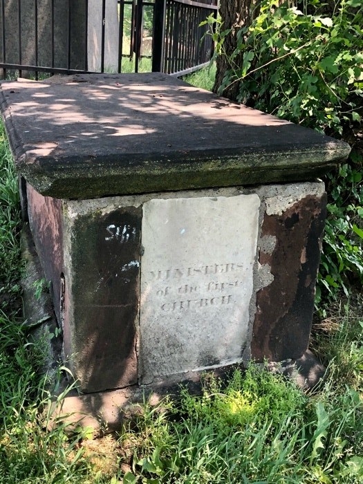 A dark tomb on a sunny grassy area