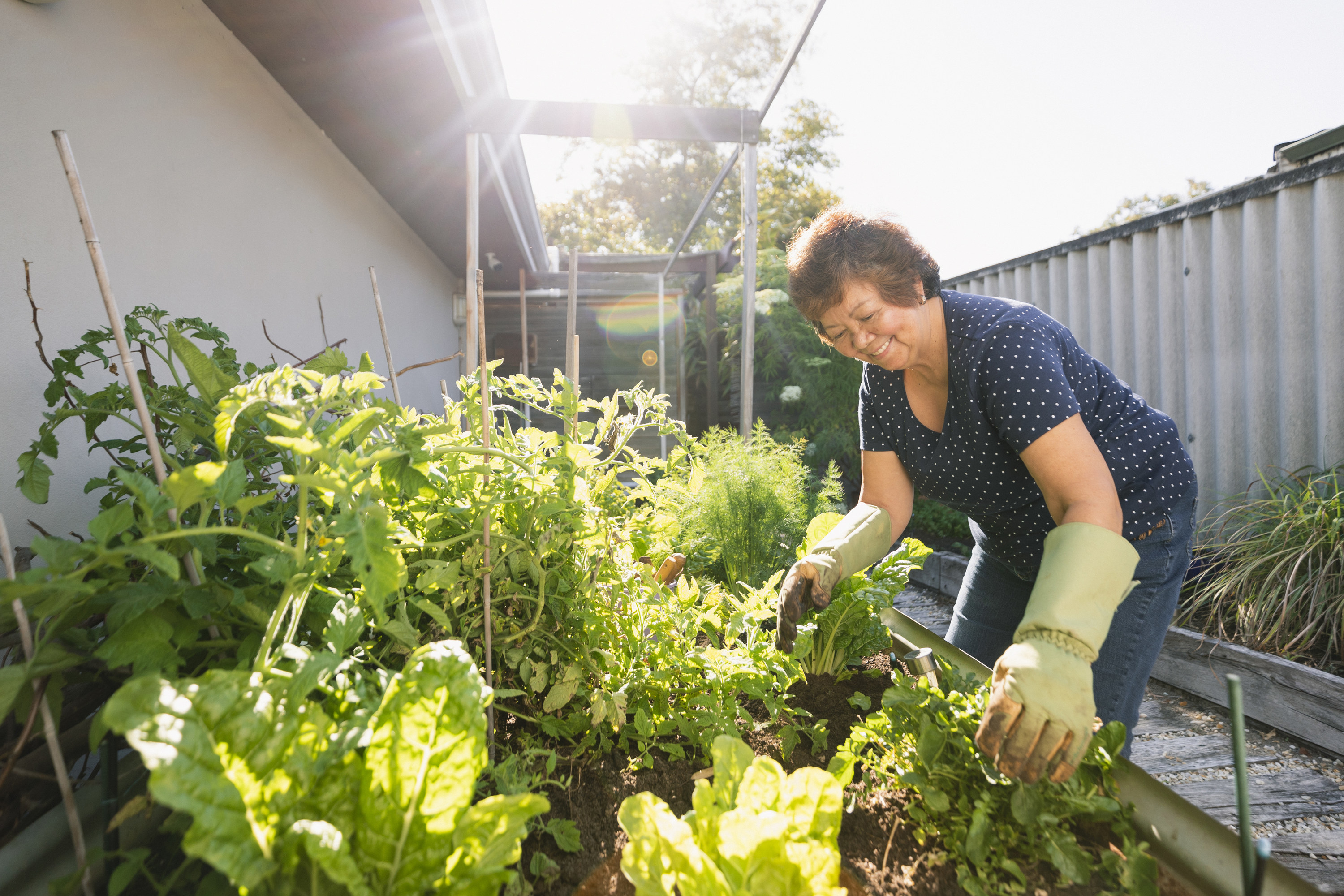 A smiling woman tends to her sunny outdoor garden