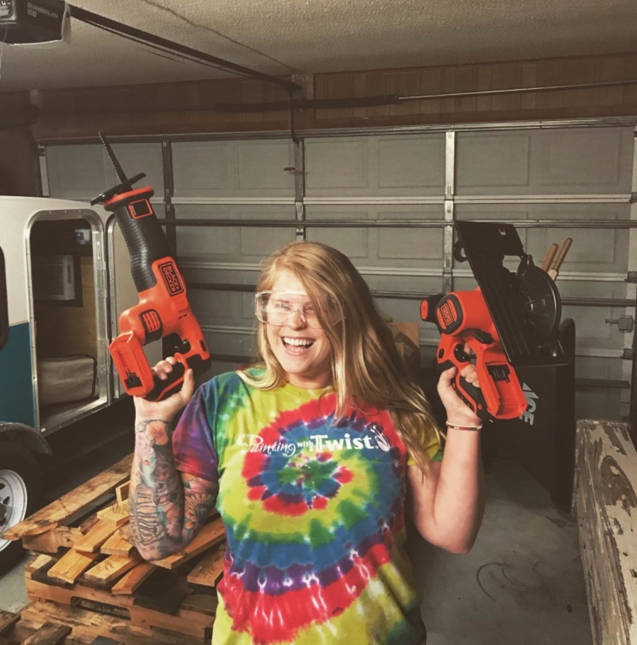 Reviewer is holding two power tools in each hand while smiling