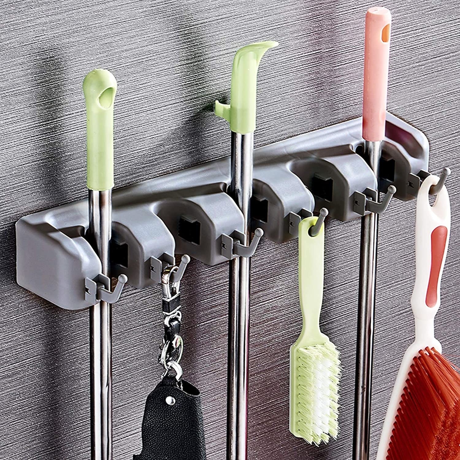 Cleaning supplies hanging off of the wall-mounted mop storage rack