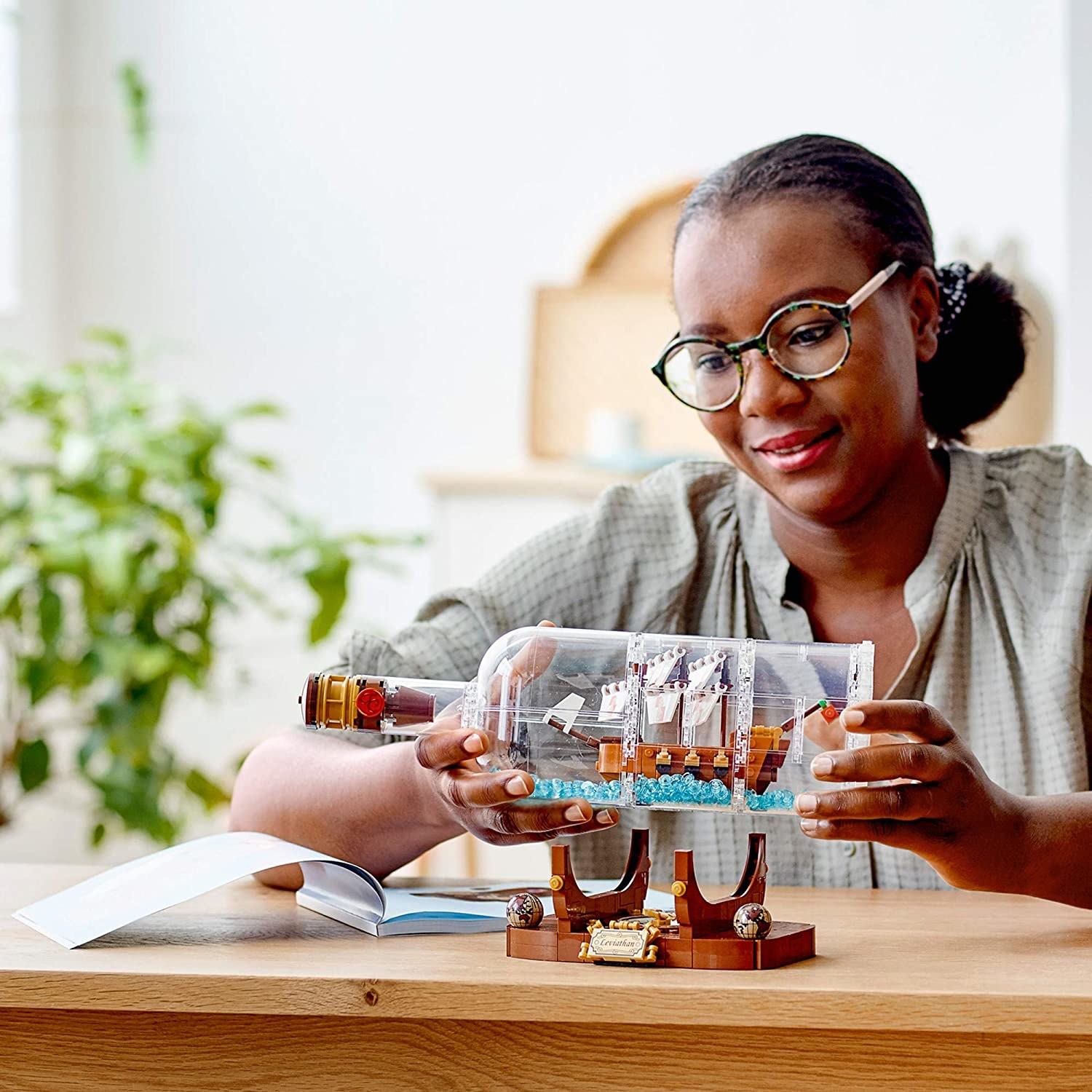 Model holding plastic Lego ship in a bottle toy
