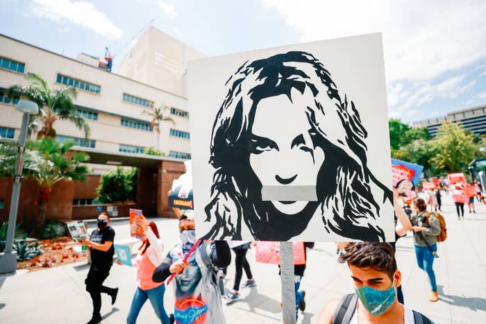 A Britney Spears fan holds up a sign that shows an illustration of the pop star with duct tape over her mouth