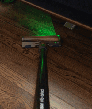 a gif of the vacuum using a green laser light to highlight the dirt under a bench