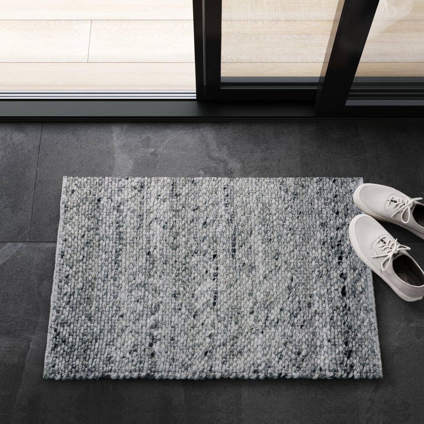 small grey wool woven rug on the floor next to a pair of shoes