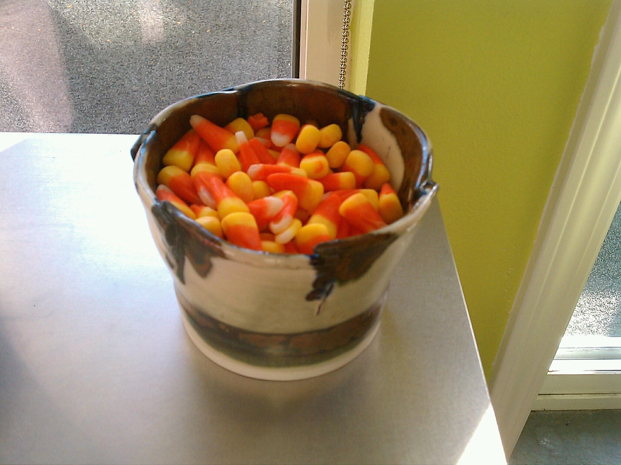 A bowl of candy corn sitting on a counter.