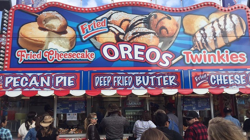 A fair stall that shows an array of deep fried menu items including Twinkies, butter, Oreos, cheesecake and cheese.