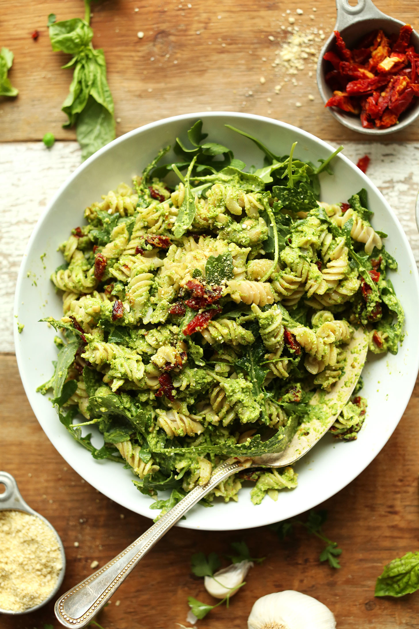 Plate of freshly made pea pesto pasta with bits of sliced sundried tomatoes.