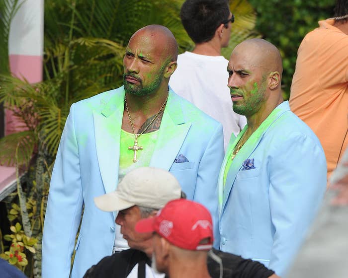 Dwayne and his stunt double both wearing pale blue suits that are stained in green paint