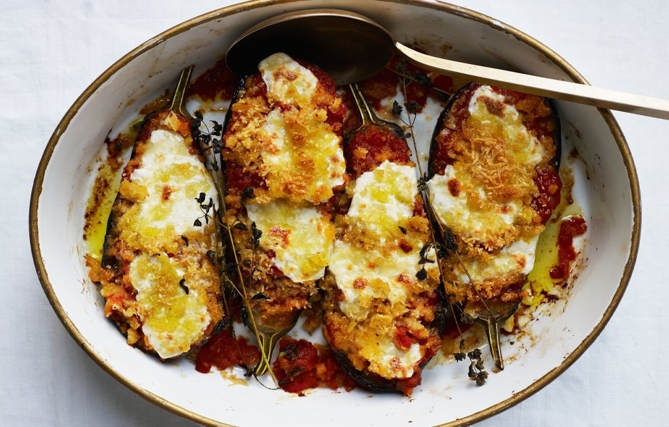 A casserole dish with eggplant parmesan with herb sprigs decorating it.