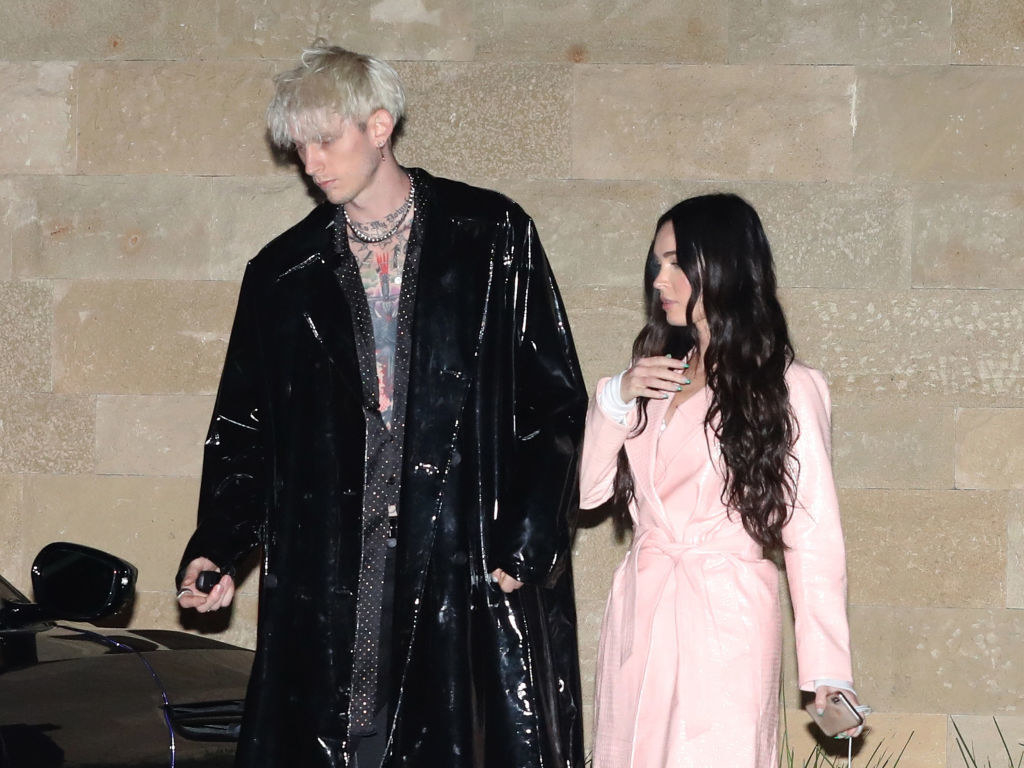 He has a long, slick coat, and she has a pastel coat that looks like a Victorian dress