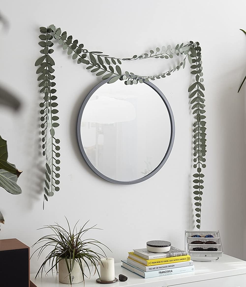 A circular mirror hung on a wall above a neatly arranged dresser