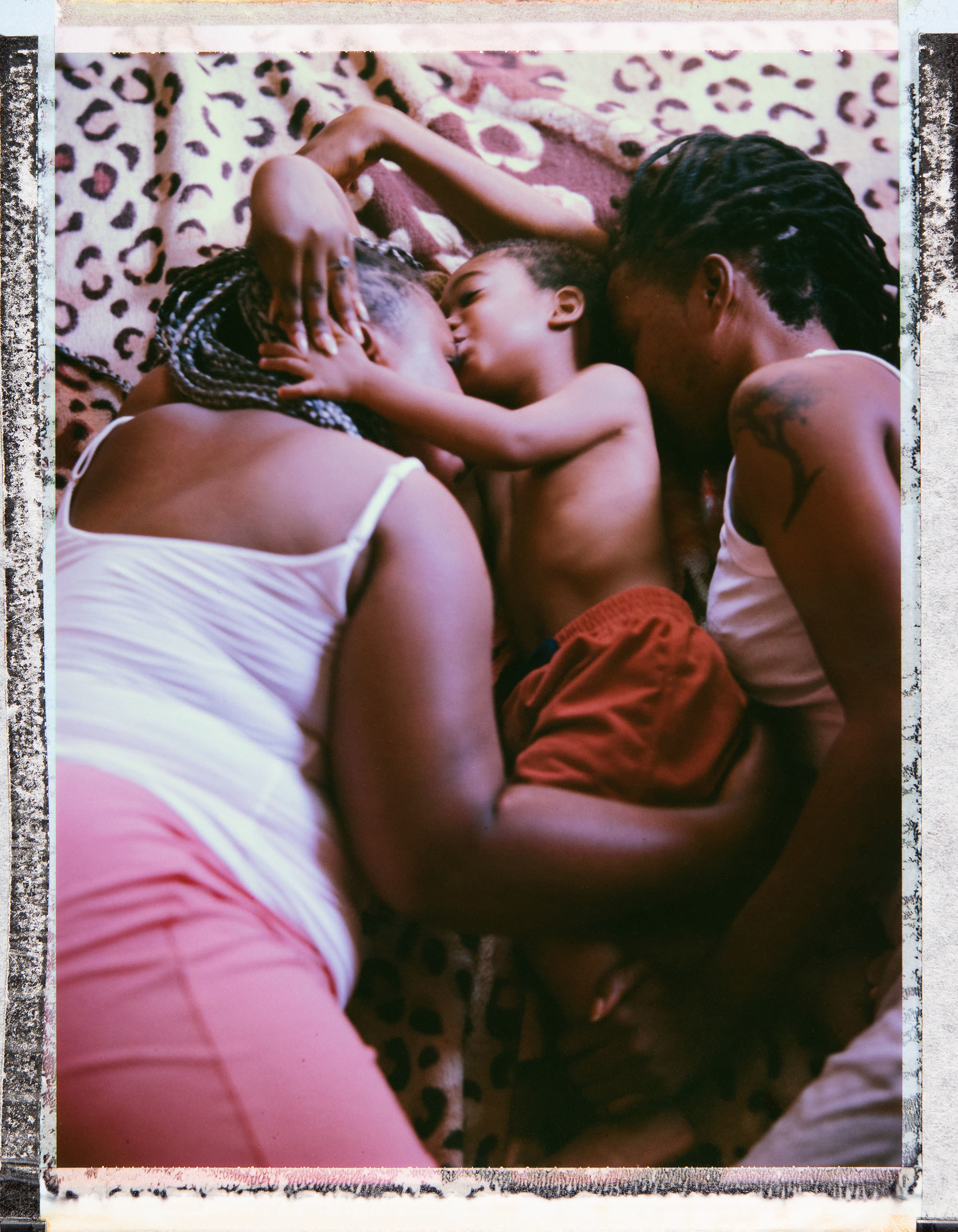 Two women hug a young boy lying down between them