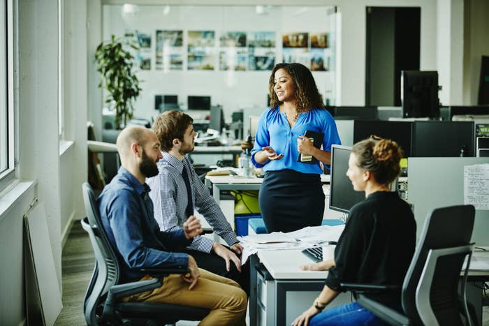 An image of co-workers sitting around a table in an office