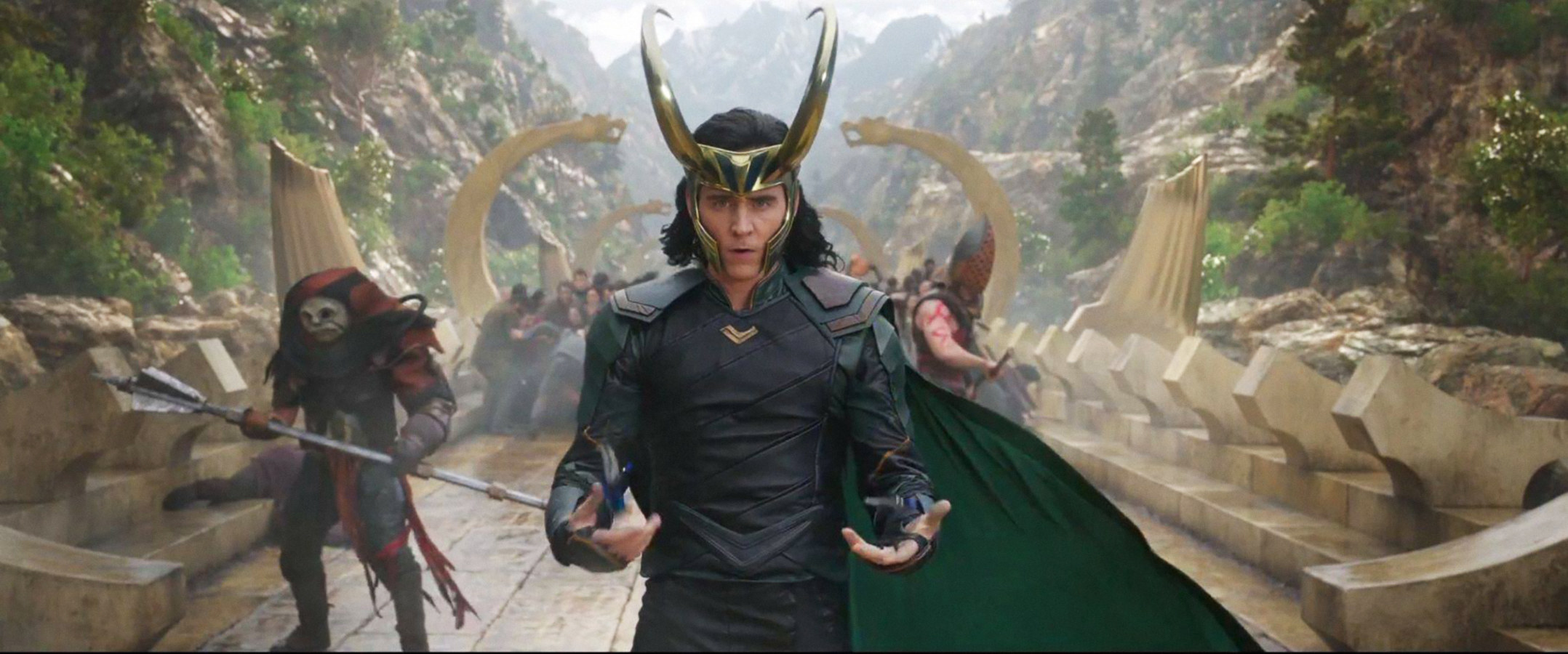 Loki on a bridge wearing a cape and horns