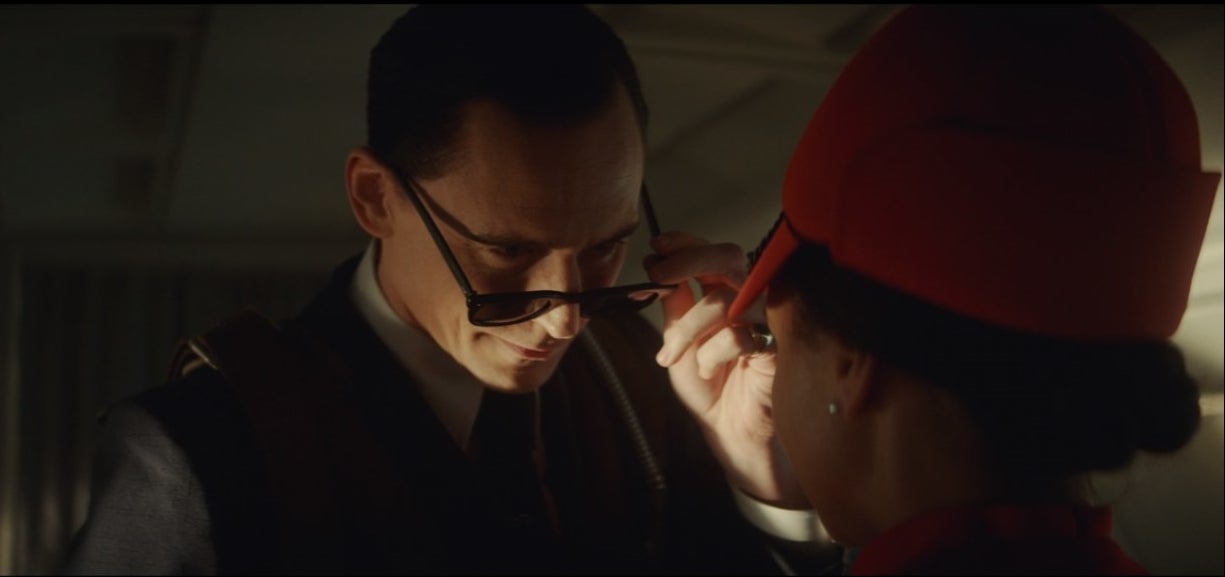 Loki looks over his sunglasses at a flight attendant
