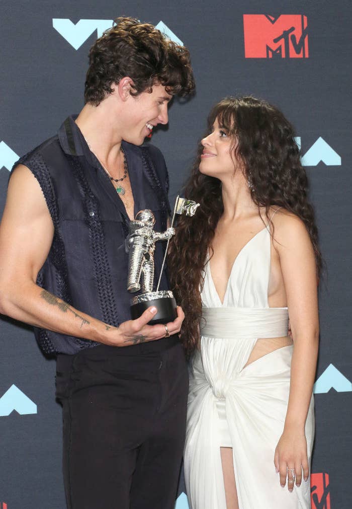 Shawn Mendes has a sleeveless denim shirt, and Camila Cabello has a toga dress