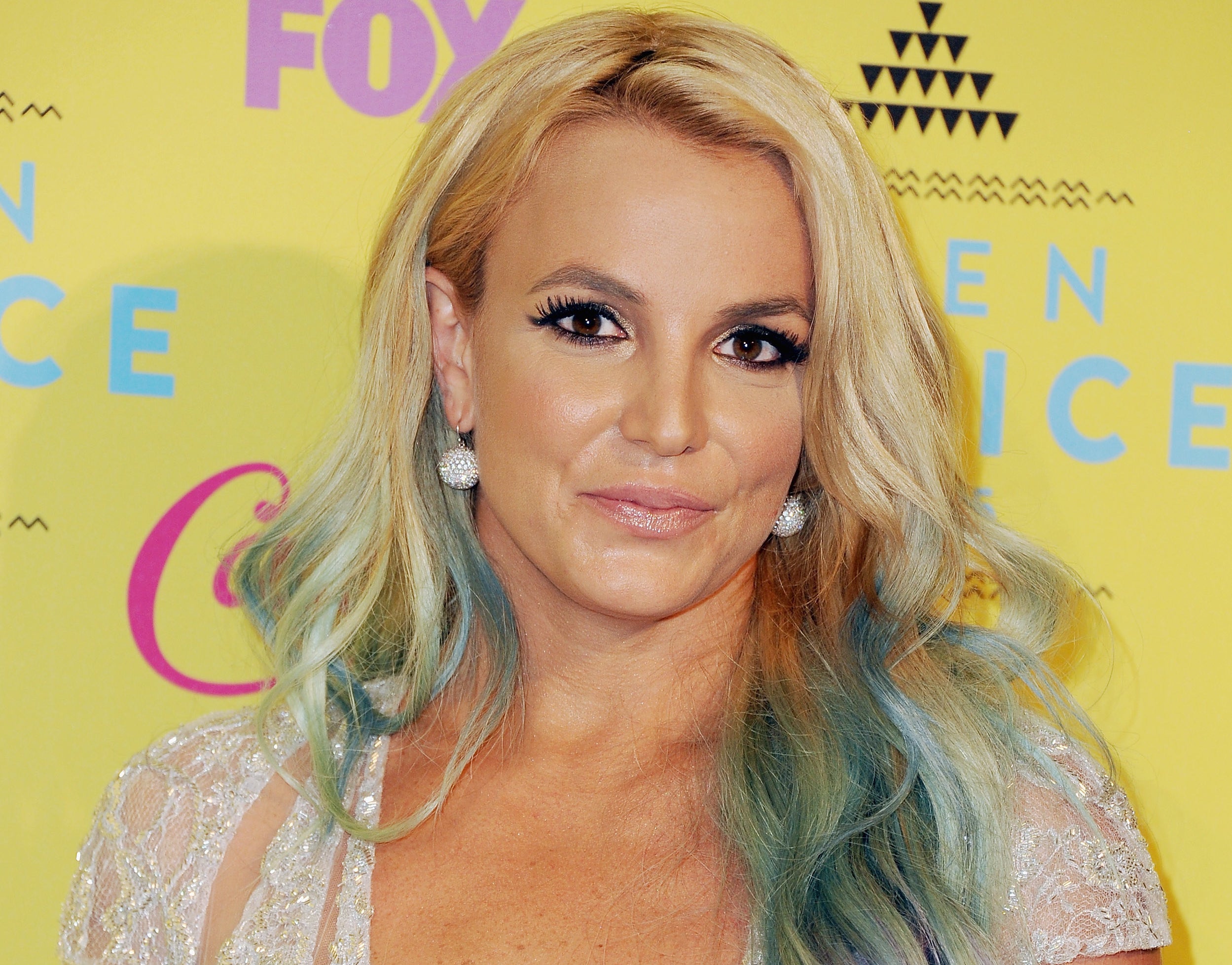 Britney smiles softly while showing off blue streaks in her hair