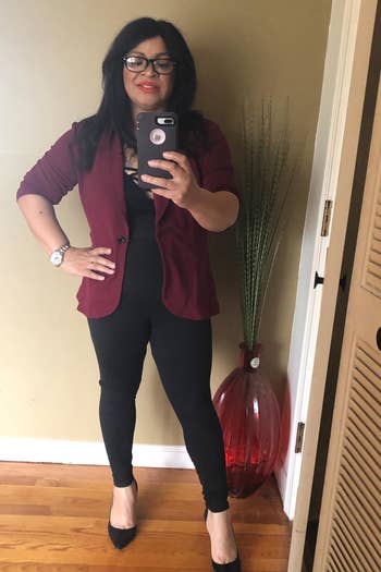 a reviewer mirror selfie of someone wearing the leggings with heels and a blazer 