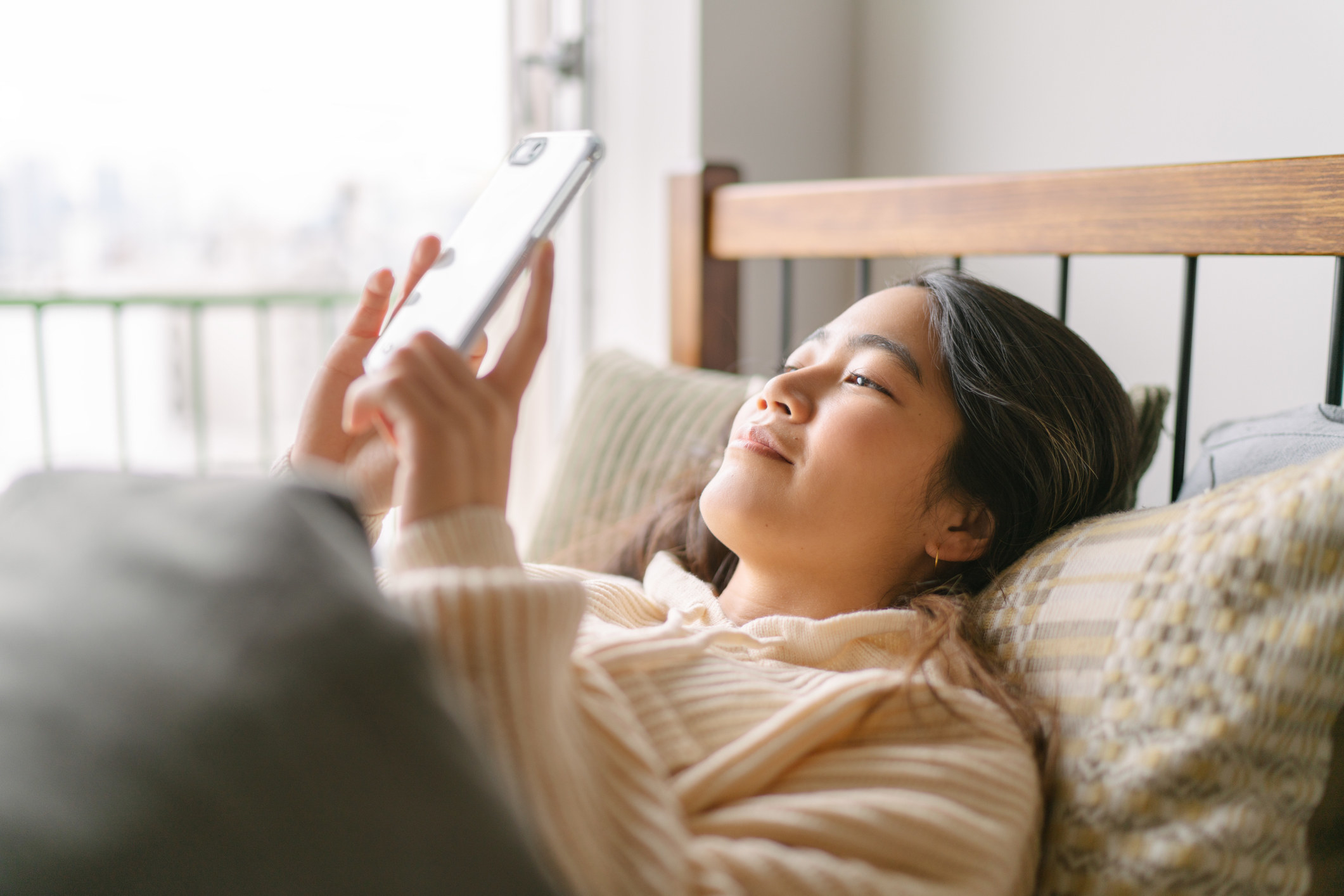Woman grinning at her phone in the morning