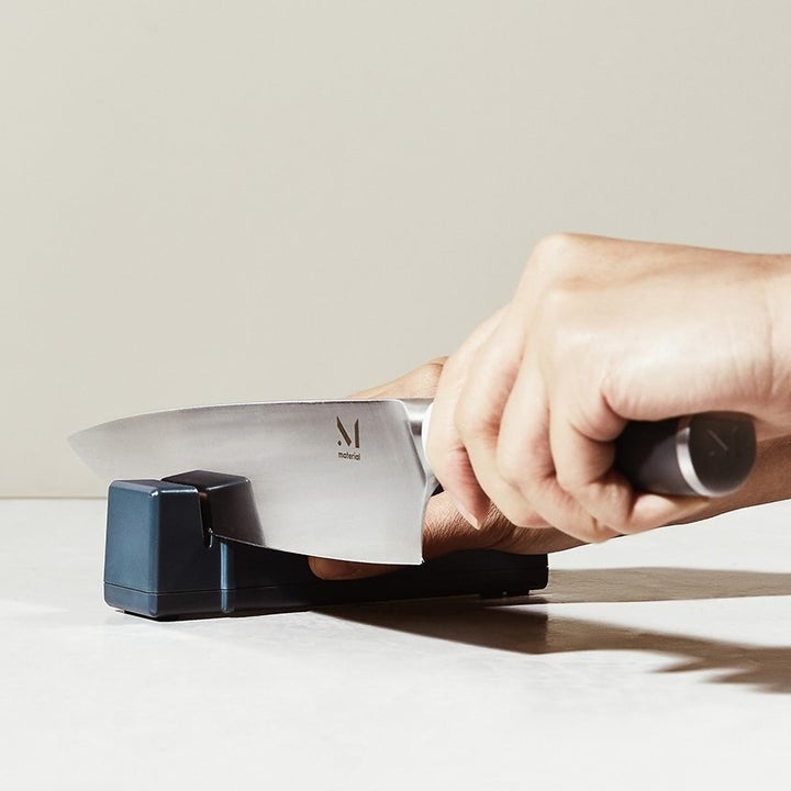 a model running a knife through a blue knife sharpener 