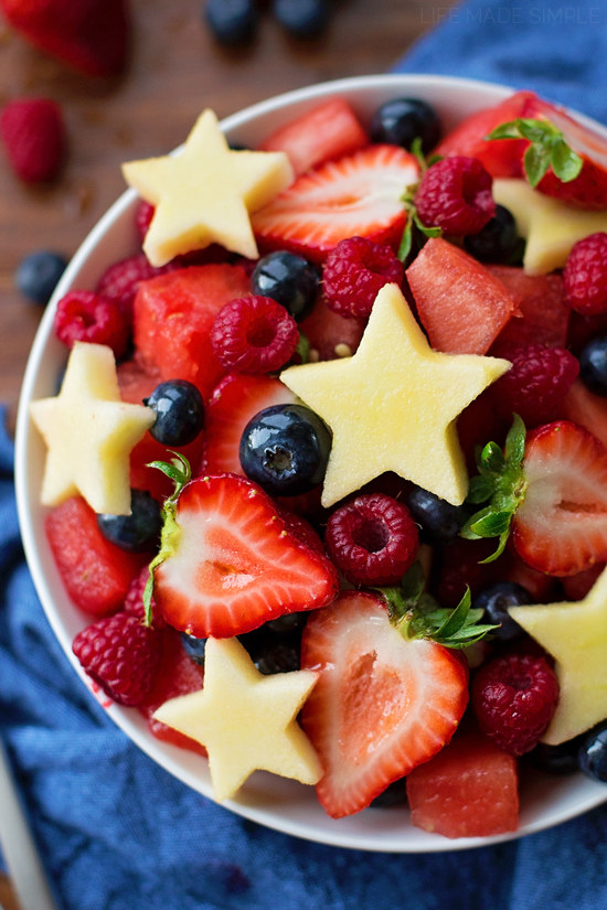 Fruit salad with star-shaped apples, blueberries, raspberries, and strawberries.
