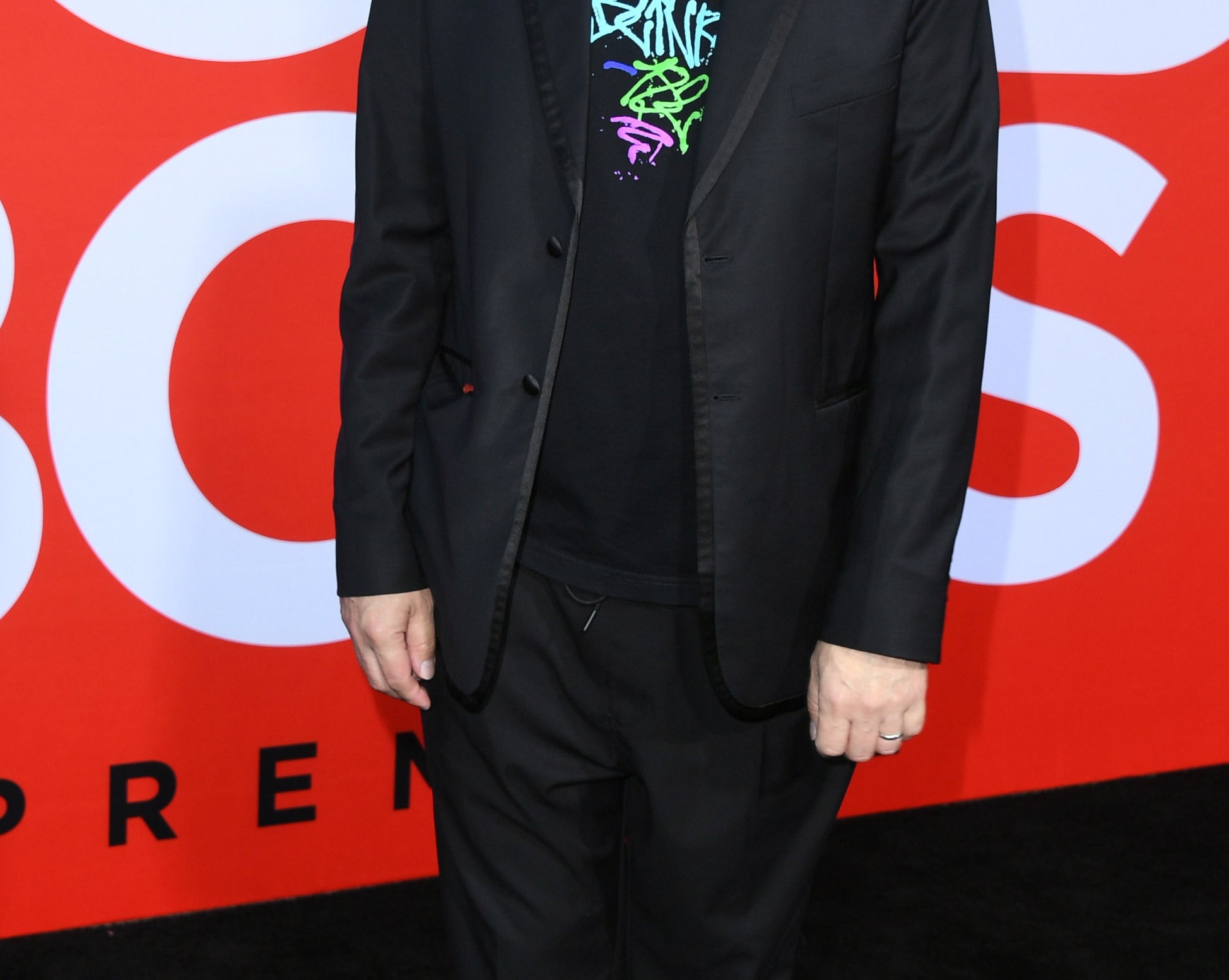 Mark wears sunglasses and a suit jacket over a Blink 182 t-shirt