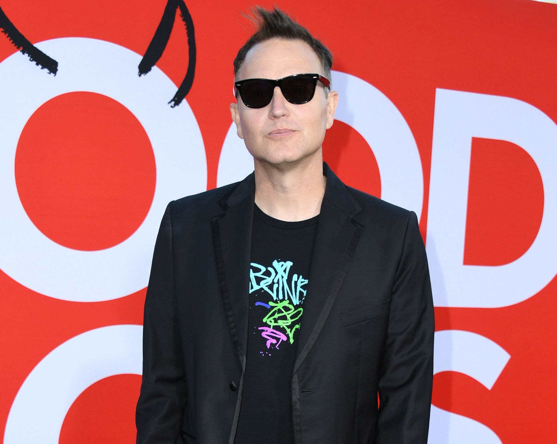 Mark wears sunglasses and a suit jacket over a Blink 182 t-shirt