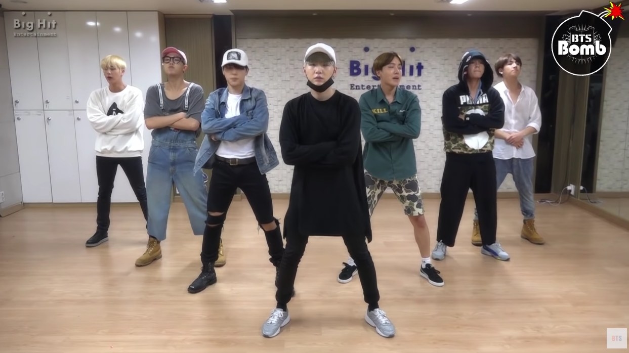 BTS stand in formation with their arms crossed in their former dance studio