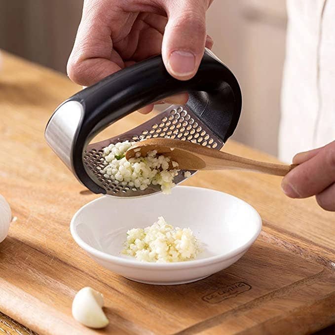 Garlic minced with the crusher transferred into a white ceramic bowl.