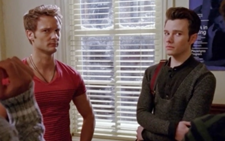 Adam, wearing a black and red striped shirt, stands next to Kurt who&#x27;s wearing a grey pull over sweater and looking incredibly uncomfortable.