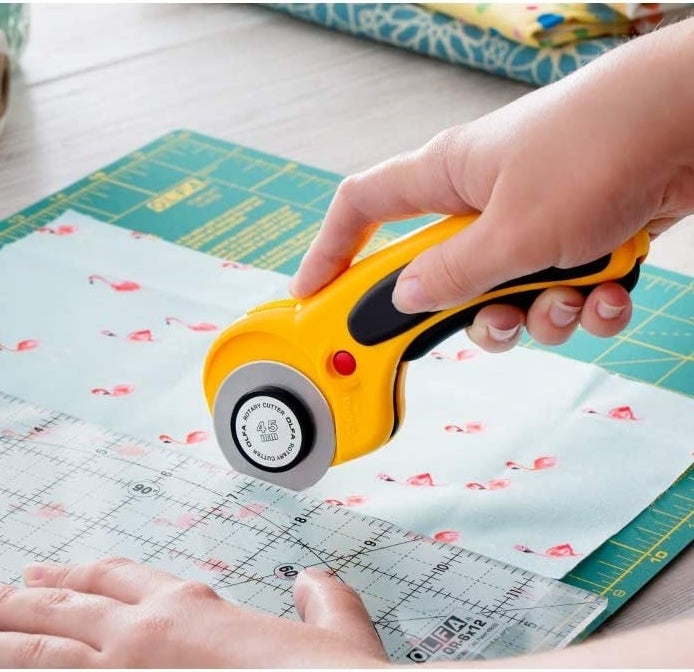 A person using the rotary cutter on fabric