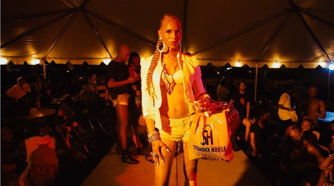 A woman stands on a raised runway at a kiki event