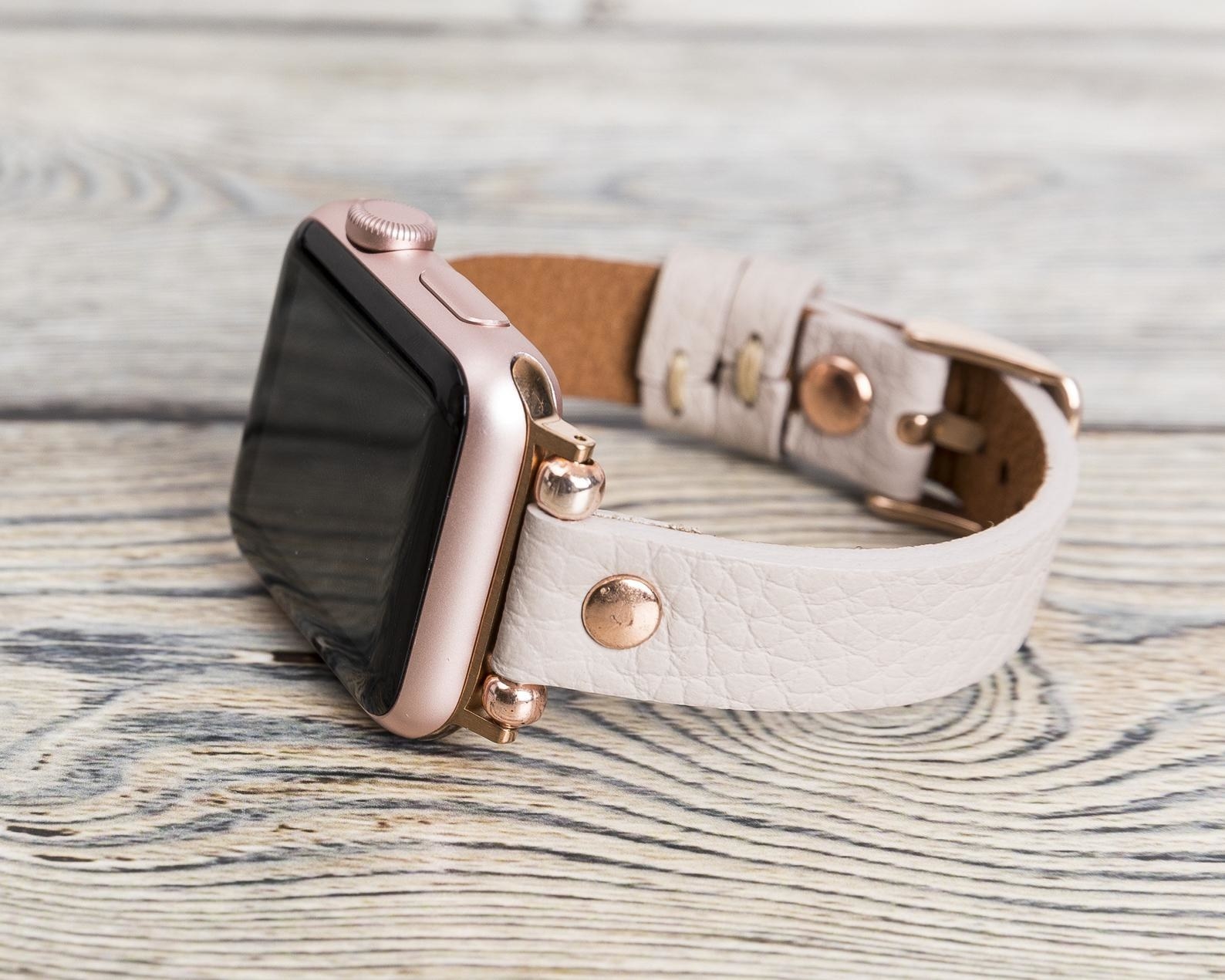 a light gray leather watch band with rose gold accents