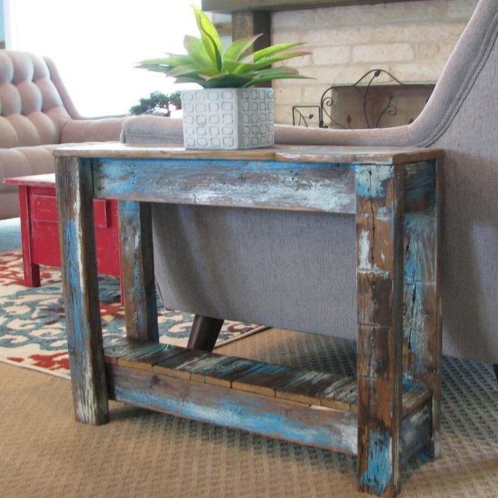 a heavily distressed blue and brown painted side table with a plant on it