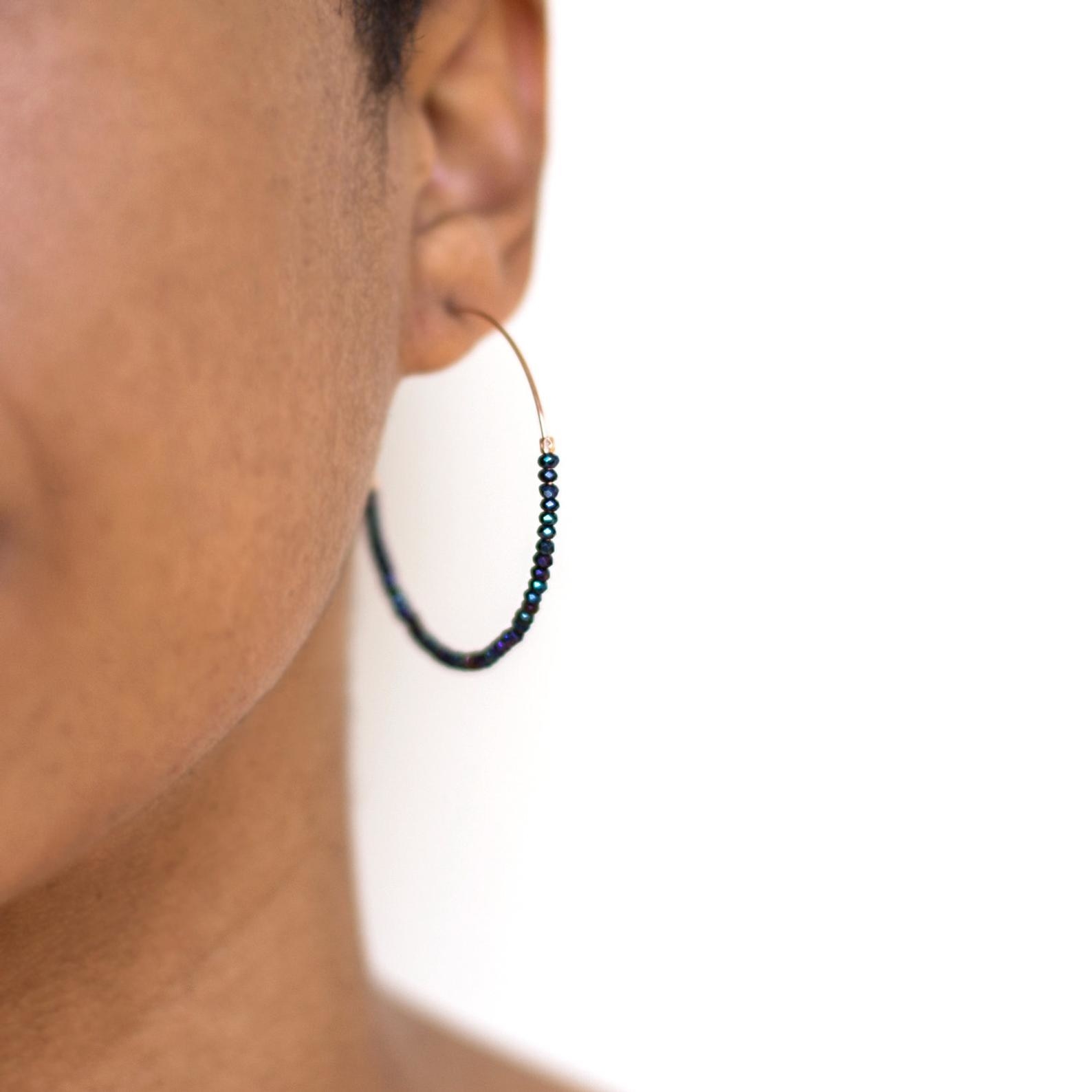 a model wearing thin hoop earrings with bead strung along them
