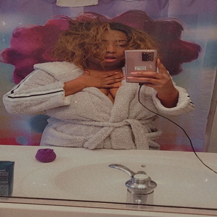 reviewer mirror selfie looking shocked and disheveled, purple rose vibrator on the sink counter
