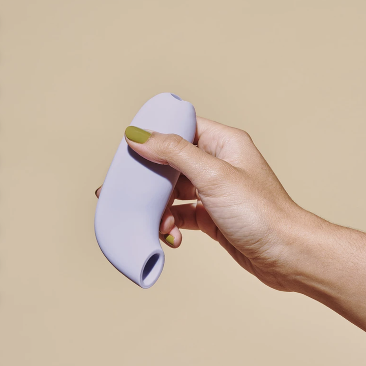 product image of a hand with green painted nails holding the Dame vertically