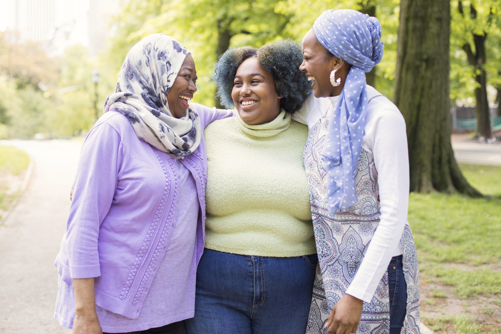 Three Muslim woman laughing together at a park