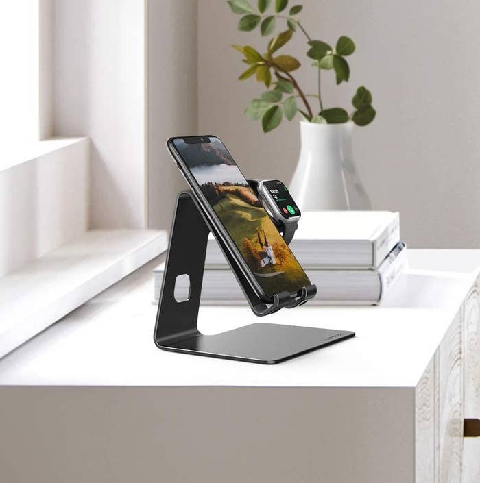 The stand with a phone and watch on it