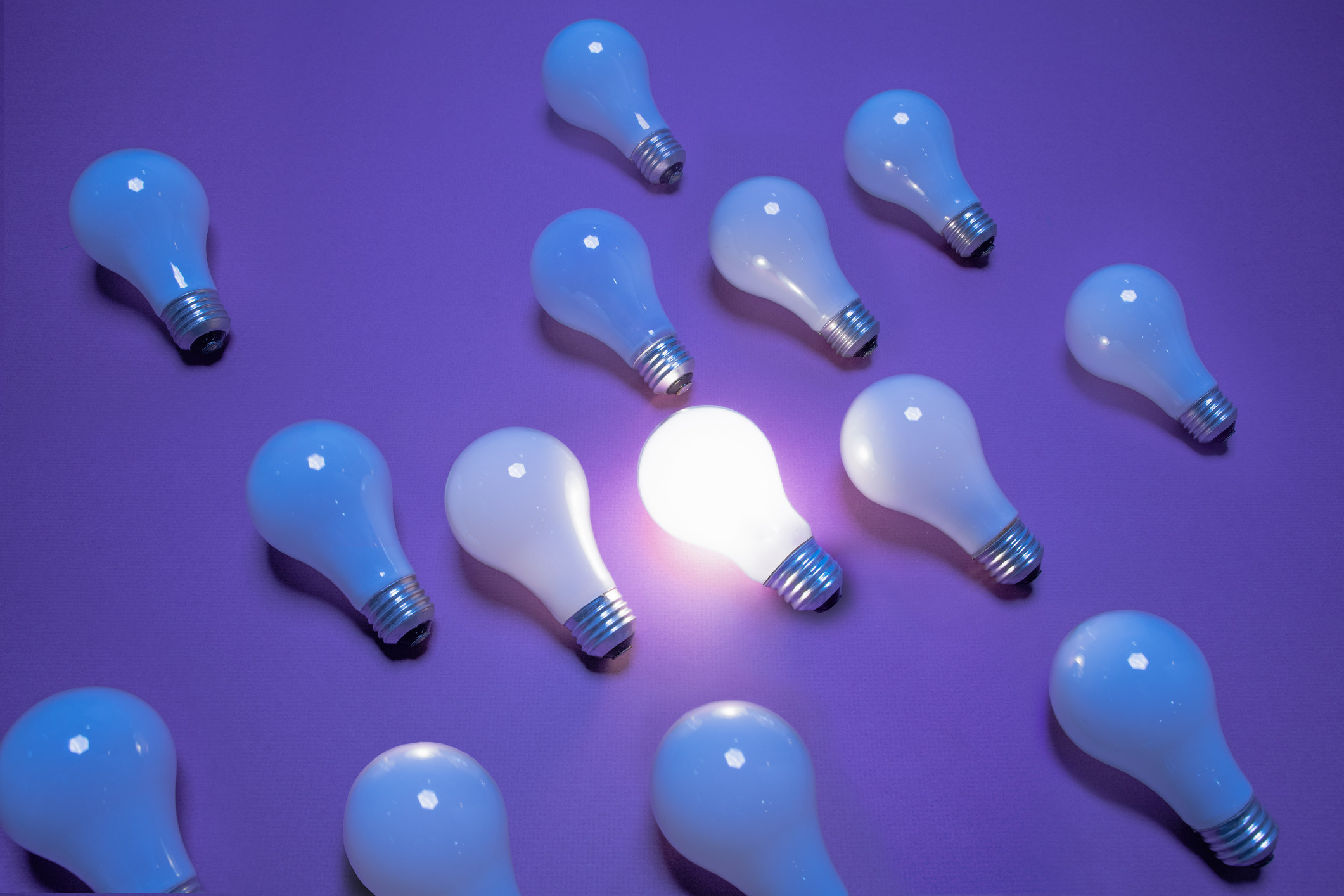 A group of lightbulbs laid out with one on and the others off